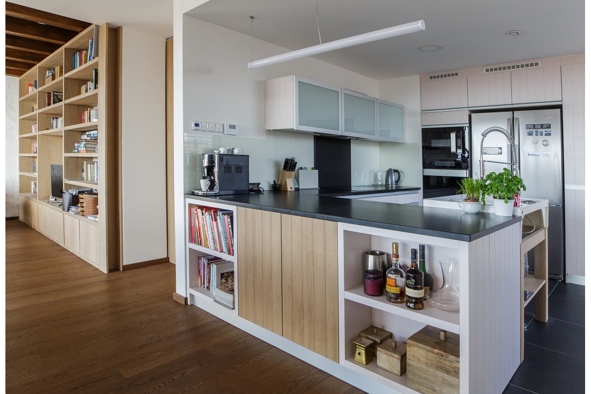 Family house interior - Kitchen with a free-standing sink and granite worktop, sprayed with a “powder” colour. Behind, a slightly open door to the pantry, hidden in the kitchen’s storage space system.