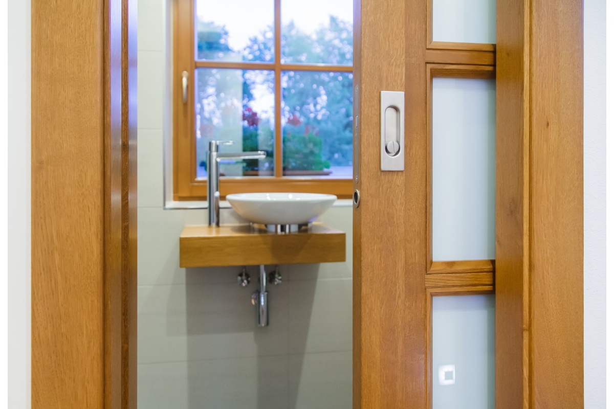 Interiér rodinného domu - Na koupelnu rodičů navazuje šatna s dubovou vestavěnou skříní s posuvnými dveřmi z mléčného skla. Šuplíky mají praktické i krásné vyprofilované úchytky.	