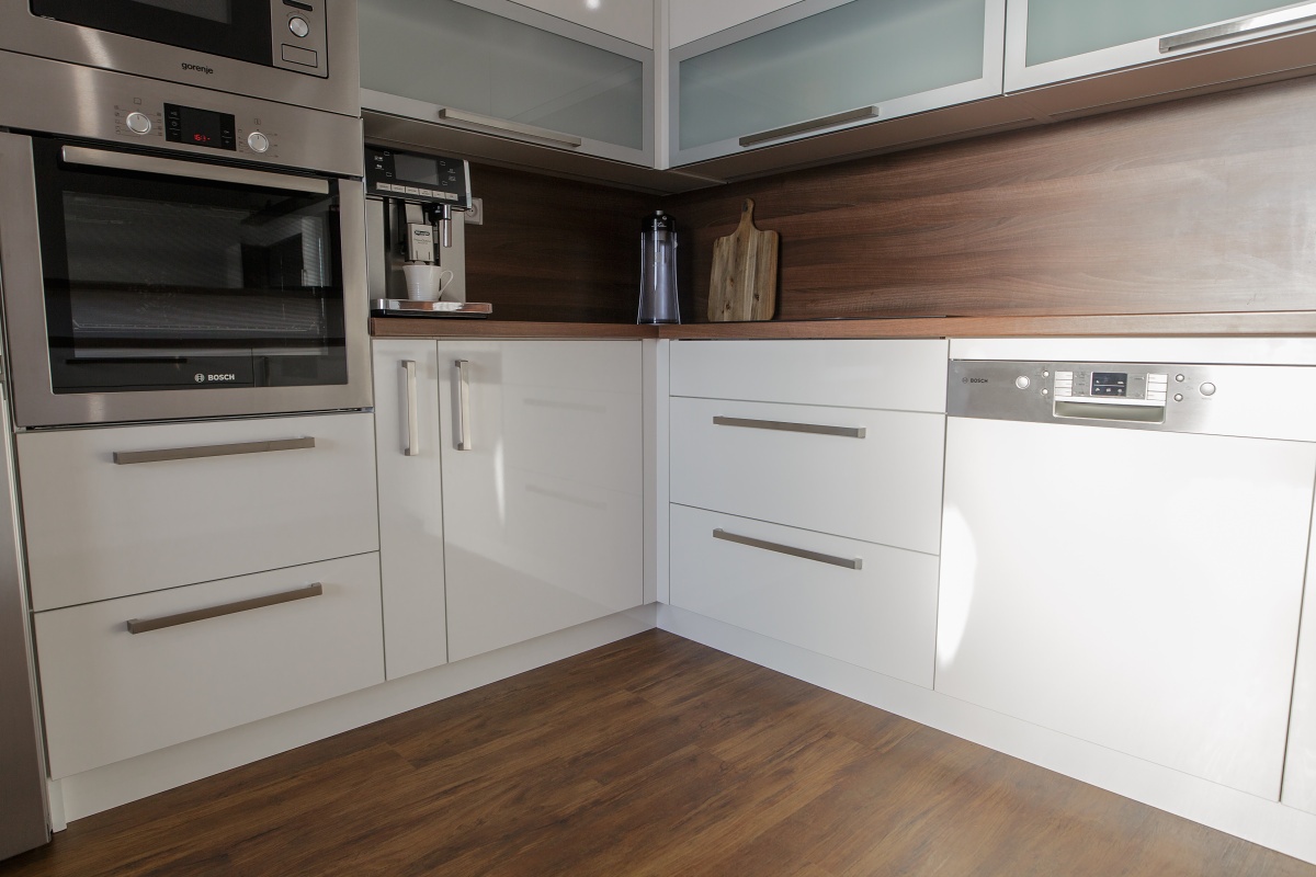 Family house  - The kitchen combines high gloss with walnut laminate. The owners opted for an unconventional exhaust hood, built in directly in the hob. A first-rate Blum ironwork is a matter of course.	