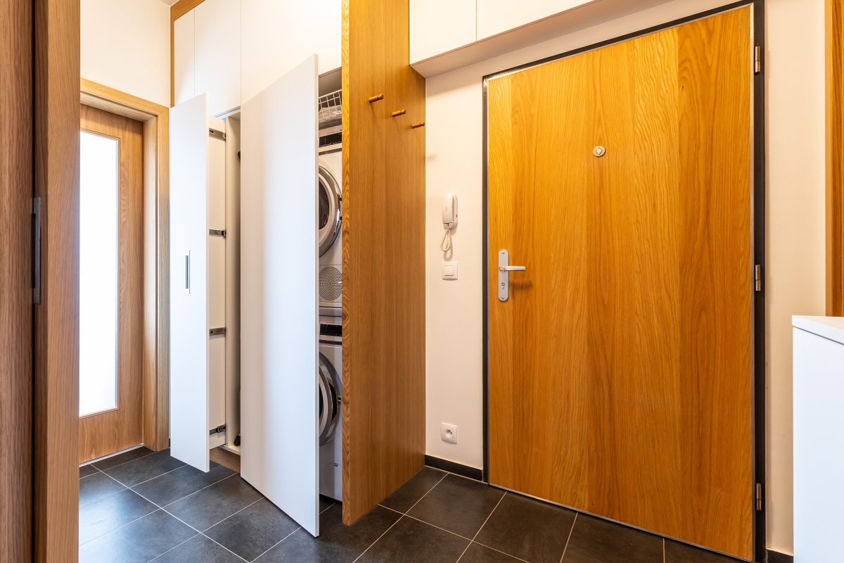 Interior of Apartment in New Building - The vestibule contains a closet with an incorporated washing machine and dryer. The tailor-made storage space has room for an ironing board and cleaning supplies. 