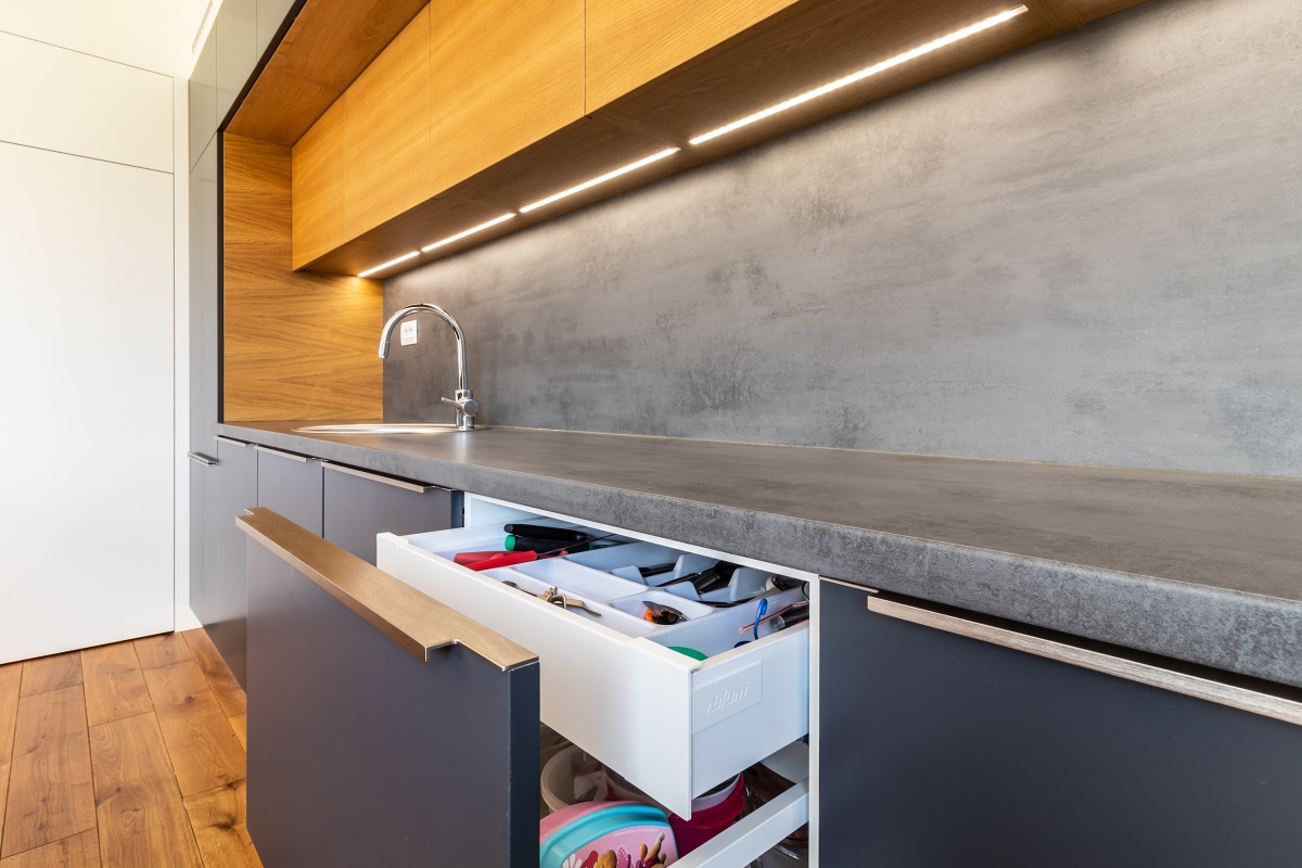 Family House  - The unobtrusive stainless-steel handles do not interrupt the clean lines of the kitchen unit. Some sliding-out cabinets hide other smaller drawers for smaller kitchen utensils. 